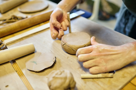 A girl with a string in her hands cuts the top layer off clod clay.の写真素材