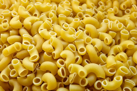 Uncooked italian pasta background. Elbow Macaroni with a smooth surfaceの写真素材