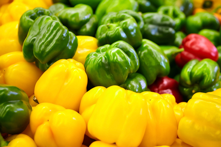 Yellow, green and red sweet bell peppers  on a counter in the supermarketの写真素材