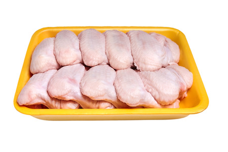 Raw and uncooked chicken wings in a yellow plastic container. Meat of poultry in tray, isolated on white background. Top viewの写真素材
