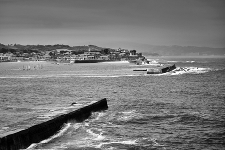 Saint Jean de Luz, France. Basque country. City views Ciboure and Castle and port of Socoa. Sailboats. Ocean waves breaking about the dam. Black and white photographyの写真素材