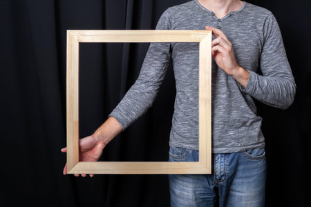A man holds in his hands a square wooden subframe for stretching canvas