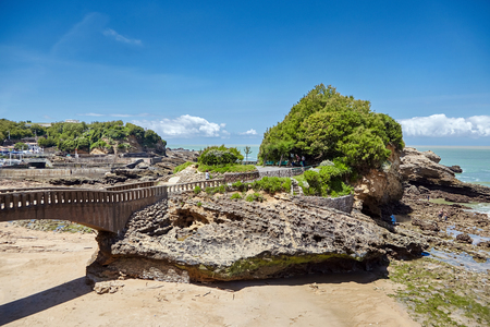Biarritz, France: Rocher Du Basta island. Park and old stone bridge. Low tide. Seascape. Atlantic Coast. Summer dayの写真素材