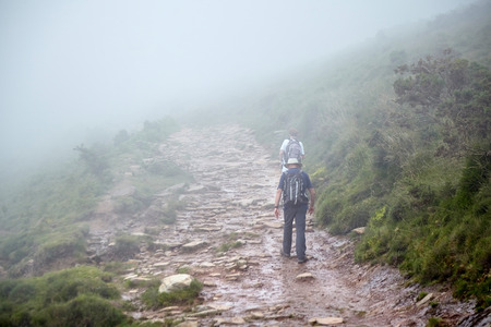 Couple of hikers walking in mountains. Hiking trail in the Pyrenees. La Rhune mountain, Franceの写真素材