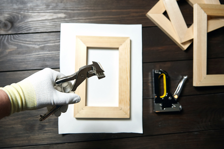 Stretching cotton canvas on wooden stretcher bar, canvas pliers in a handの写真素材