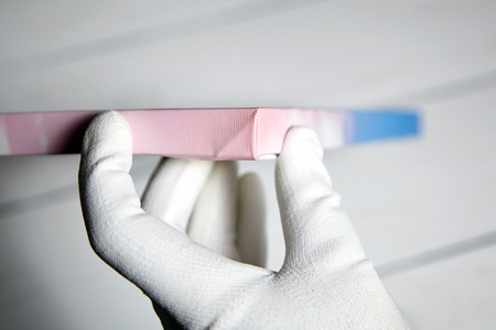 Gallery wrap, photo printed on glossy synthetic canvas and stretched on wooden stretcher bar, lateral side closeup. Male hand holding a photography printの写真素材