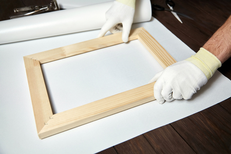 Canvas, wooden stretcher bar and male hand in white protect glovesの写真素材