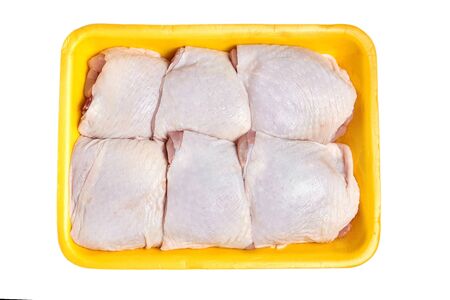Raw chicken thighs in a yellow tray isolated on white backgroundの写真素材