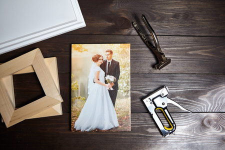 Photo of a wedding couple printed on canvas. Photography on a wooden table. Stretching canvas tools,...
