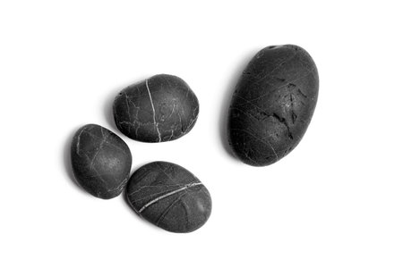 Scattered sea pebbles. Four black stones. Smooth rocks isolated on white background.  Top view