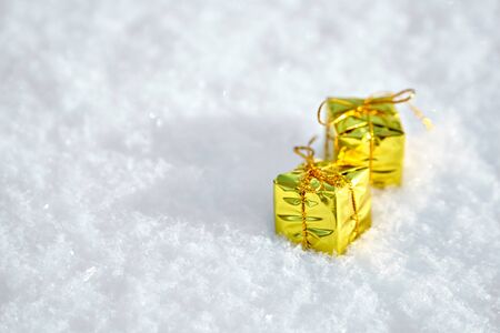 Golden Toy Gift Boxes lie on the natural snow. Winter Christmas and New Year background. Frosty weather with loose snowy surface in wintertimeの写真素材