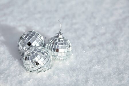 Bauble, toy mirror disco balls lie on the natural snow. Winter Christmas and New Year background. Frosty weather with loose snowy surface in wintertimeの写真素材