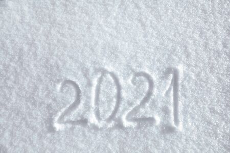 Numbers, calendar date, inscription 2021 on natural snowy surface in wintertime. Text, Winter New Year holiday background, top viewの写真素材