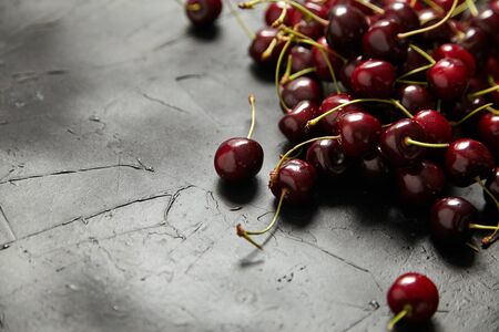 Cherries scattered on a black table. Red ripe berries on black stone tableの写真素材