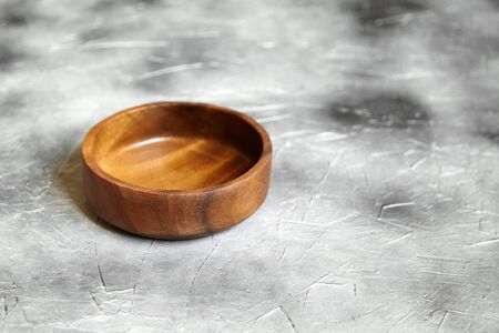 One empty wooden bowl on grey background. Single round salad bowl on stone table with black paint stains, side viewの写真素材