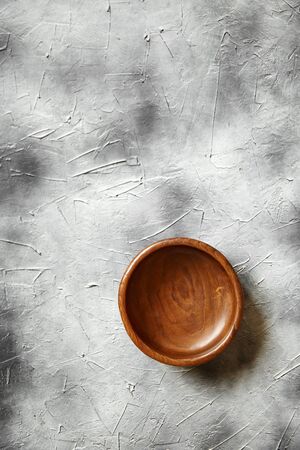 One empty wooden bowl on grey background. Single round salad bowl on stone table with black paint stains, top viewの写真素材