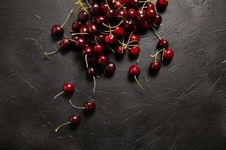 Cherries scattered on a black table. Red ripe berries on dark background, top viewの写真素材
