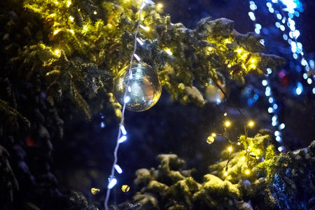 Light garland and balls on Christmas tree. Winter time, light lamp decor. Electric night holiday...