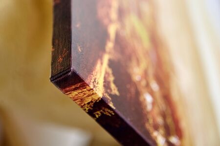 Gallery wrap canvas print without decor frame. Photo printed on a glossy cotton canvas on blurred background. Corner of photography stretched on stretcher bar, lateral side, closeup, selective focusの写真素材