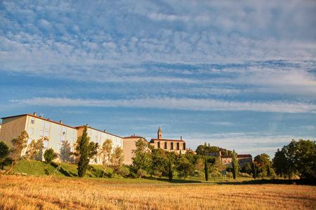 View of  the old town of Barjac, southern France. Green trees, buildings and stone church with a...