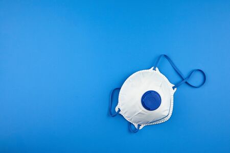 N95 respirator. Filtering facepiece respirator on blue background with copy space, top view. White FFP2 respirator, protection against coronovirus COVID-19 pandemicの写真素材
