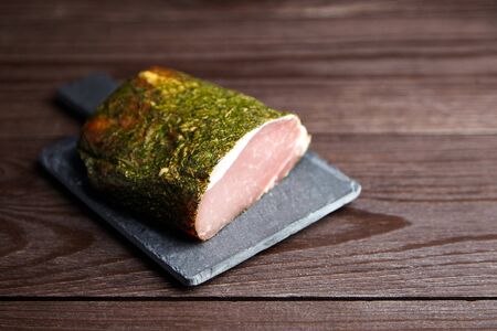 Gerky pork with spices on slate cutting board on wooden table. Polendwitz is a jerky tenderloin. Sun-dried filet, selective focusの写真素材