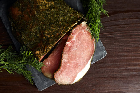 Jerky pork with spices, fresh green dill, slate cutting board on brown wooden table. Polendwitz is a jerky tenderloin. Sun-dried filet, top viewの写真素材