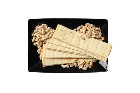 long potato chips, roasted peeled peanuts, salted beer snacks in black plate isolated on white...