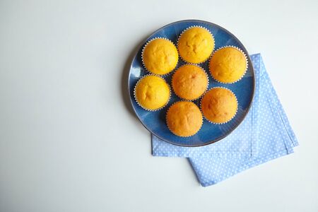 Pumpkin muffins on blue plate on white table, top view. Homemade bakery, plant-based food, vegetable muffins, sweet dessert, napkinsの写真素材
