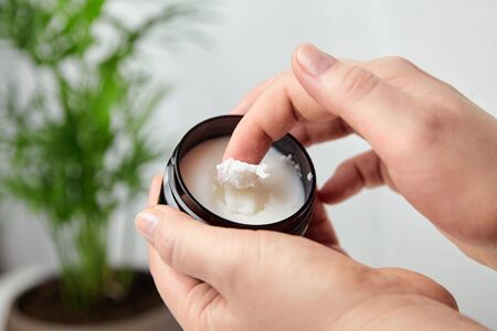 Shea butter in jar, cosmetic skin treatment product. Woman applying moisturizer to her skin of handの写真素材