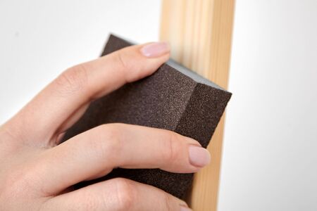 Grinding sponge block in female hand. Woman polishes the surface of a wooden easel. Grinding work. Sanding sponge, abrasive toolの写真素材