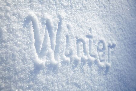 Winter background, inscription winter on snowy surface, natural snow texture with copy space, text, hand letteringの写真素材