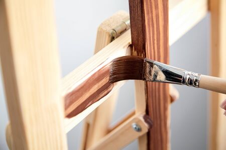 Varnish coating. Protective acrylic coating of wooden surface. Wood Finishing. Paintwork. A synthetic paint brush, board, brown color varnishの写真素材