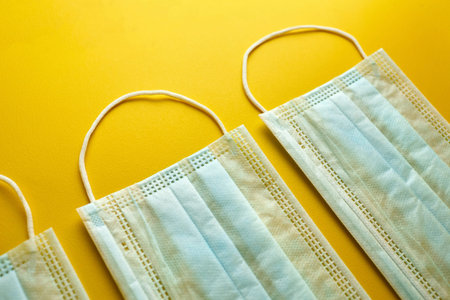 Face masks on yellow background. Medical sanitary surgical masks, anti dust breathable disposable...