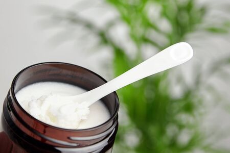 Shea butter in jar with a white ceramic spoon, cosmetic product for moisturizing skin and hairの写真素材