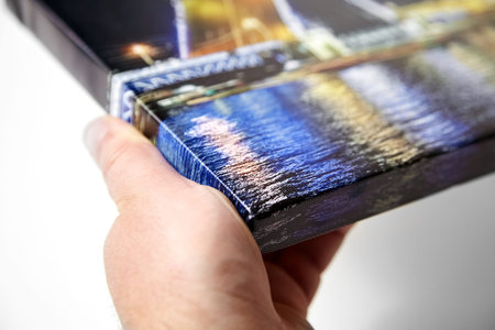 Canvas print. Hand holds a photo with gallery wrap method of canvas stretching on stretcher bar....