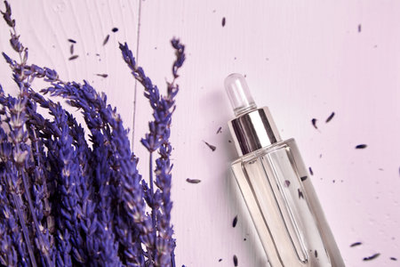Lavender cosmetic oil in a dropper bottle with glass pepit and dried lavender flowers on white...