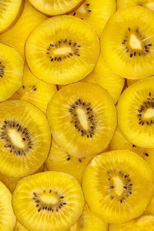 Kiwi Gold fruit background. Fresh juicy yellow kiwi slices with black seeds, top viewの写真素材