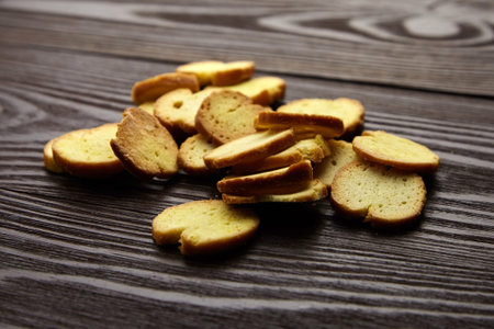 Bruschette chips, dry slices of baked bread, beer snacks scattered on wooden background