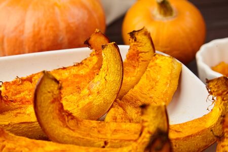 Slices of baked pumpkin in white ceramic baking tray, closeup, selective focus. Vegetable dish, vegan diet, healthy foodの写真素材