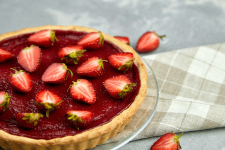 Summer strawberry pie decorated with fresh berries on linen napkin on gray background