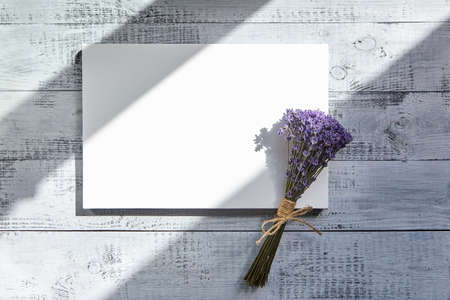 Blank canvas and flowers. Mockup, white clean canvas and lavender bouquet on wooden background with sunlight and shadows, top viewの写真素材