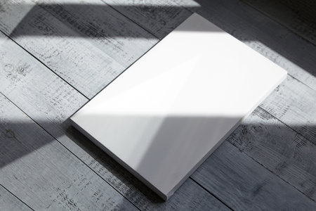 Blank canvas on gray wooden background with a shadow from the sunlight covering. Wrapped white...