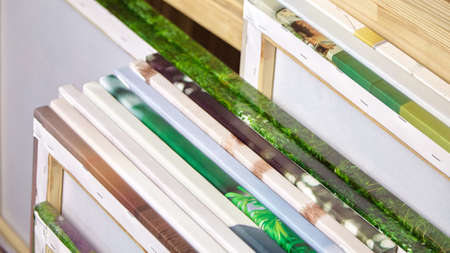 Canvas prints, stack of colorful photos with gallery wrapping method of canvas stretching on wooden stretcher bars. Samples of stretched photo canvases. Staple mount, back viewの写真素材