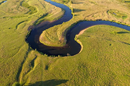 Winding river, aerial view. Summer landscape, top view. A green valley with a winding riverbed, water and grassの写真素材