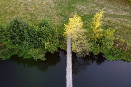 Aerial view of a simple suspension bridge over a small river. Summer landscape, river with...