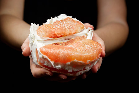 Pomelo citrus fruit with sweet red flesh on black background. Fresh juicy shaddock (Citrus maxima),...