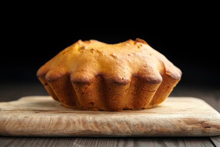 Homemade autumn pumpkin cake on wooden cutting board on dark background
