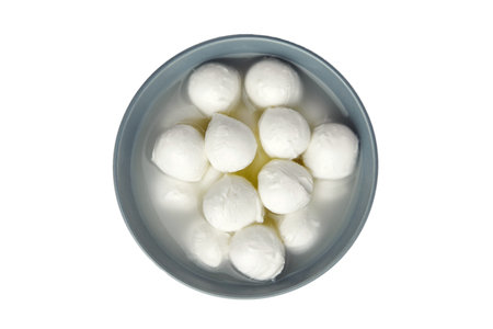 Small mozzarella cheese balls in ceramic bowl isolated on white background, top view