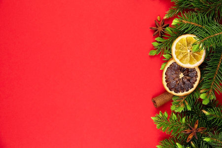 Christmas composition. Border with fir tree branches, dried orange slices and spices on red...